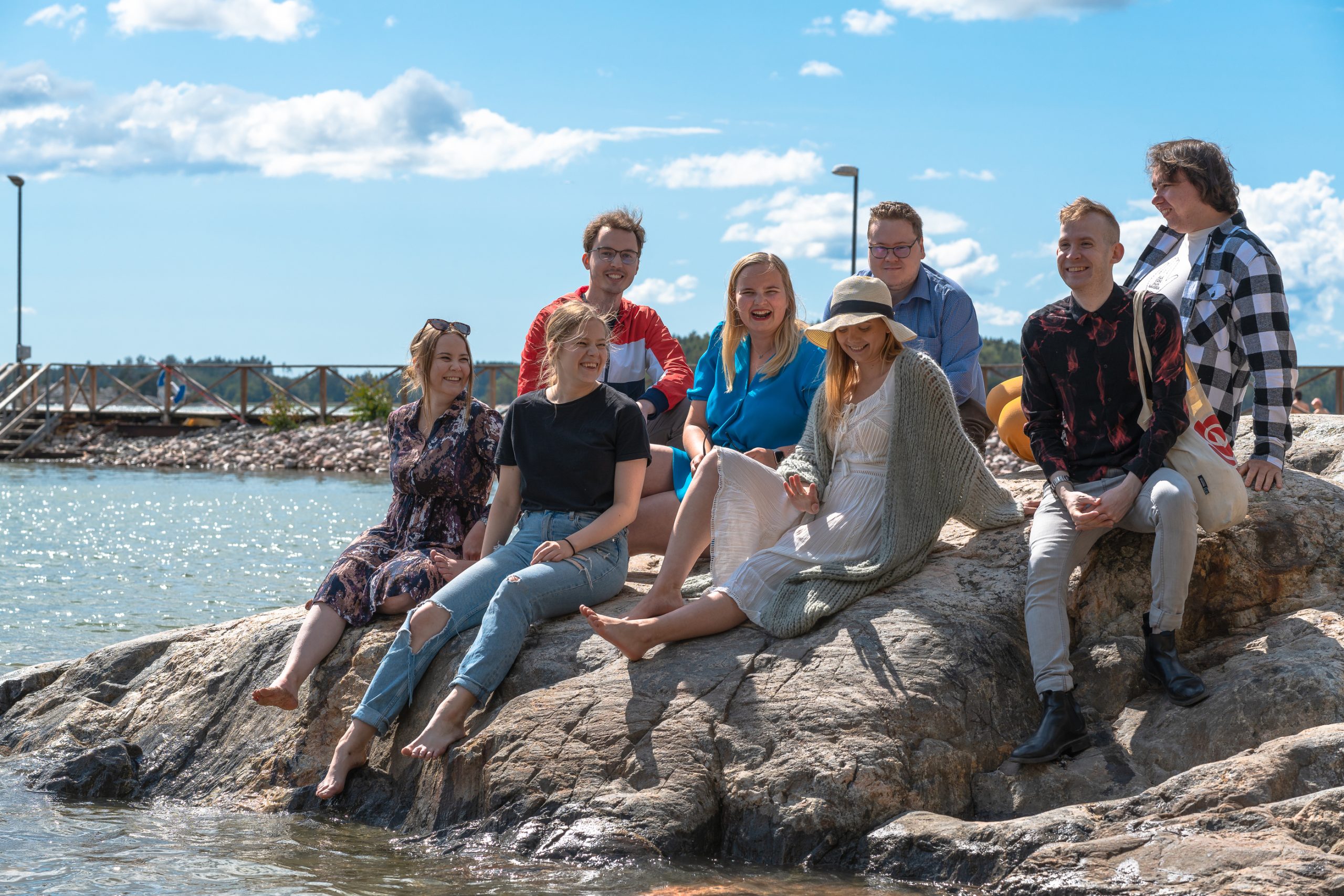 Joukko nuoria istumassa kesäisellä kalliolla.